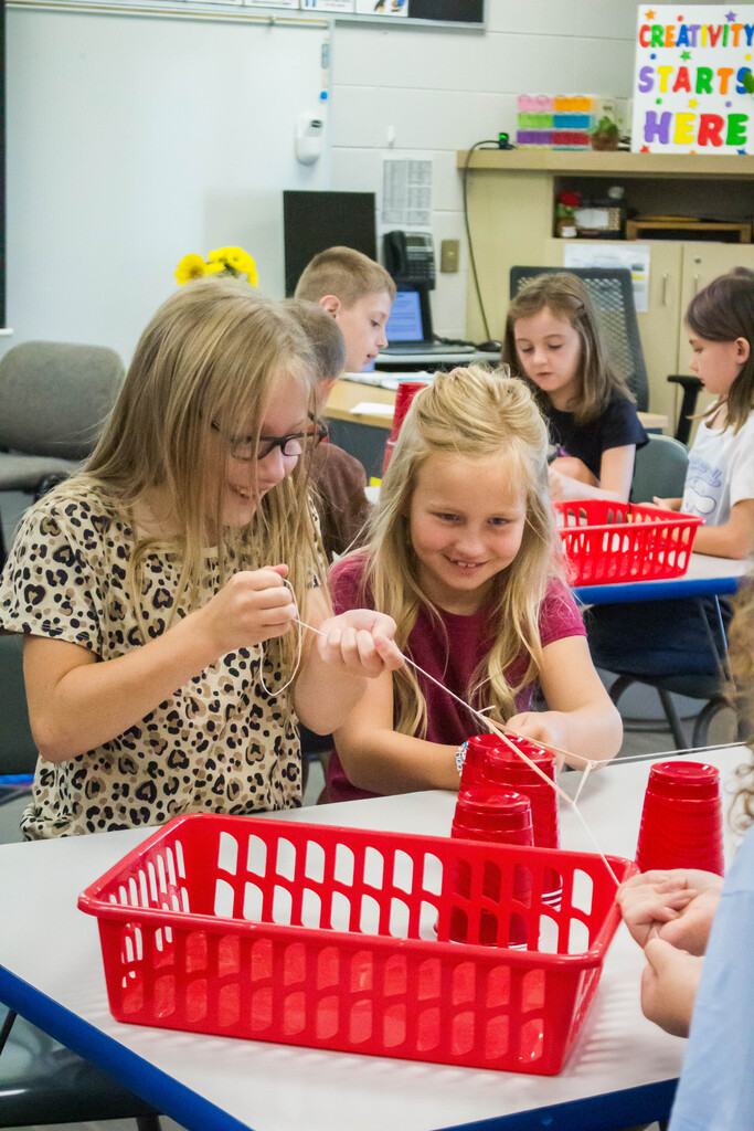 AES  students attempt cup stacking through string.