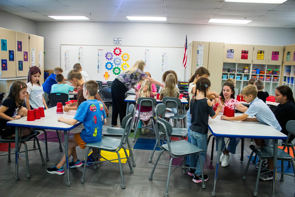 AES  students attempt cup stacking through string.