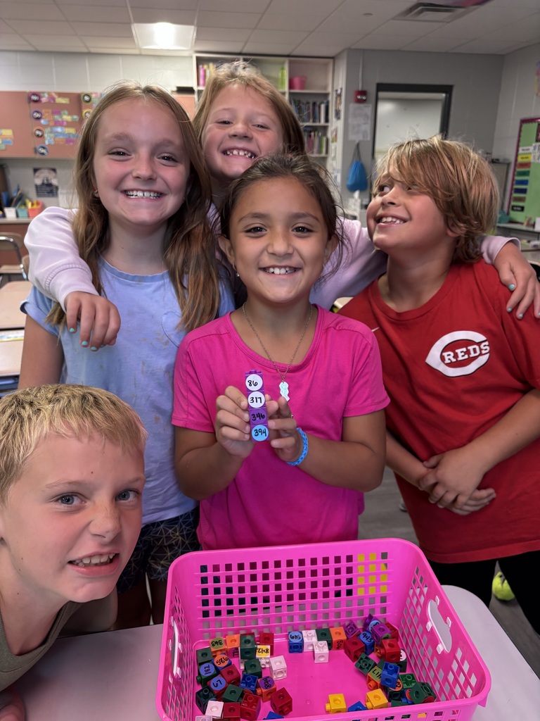 Ms. Strasemeier's 2nd grade students at Dillsboro Elementary School smiling together while holding a stack of number cubes ordered by place value.