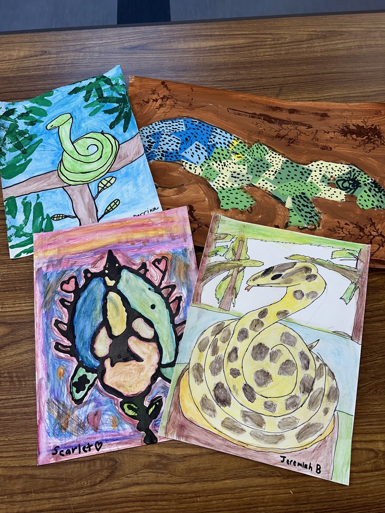 Student artwork from Aurora Elementary's South America unit showing anaconda drawings and a cut-paper jeweled lizard in mixed media.