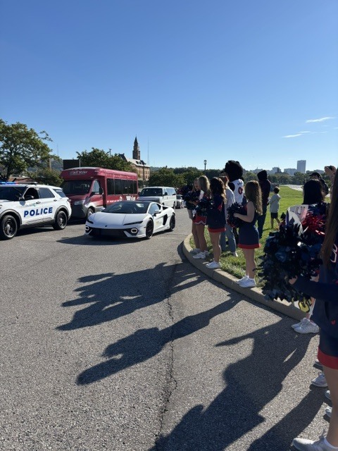 South Dearborn cheerleaders wave pom-poms as a police escort leads a white sports car carrying a VIP kid at the Jeff Wyler Fast Lane Event.