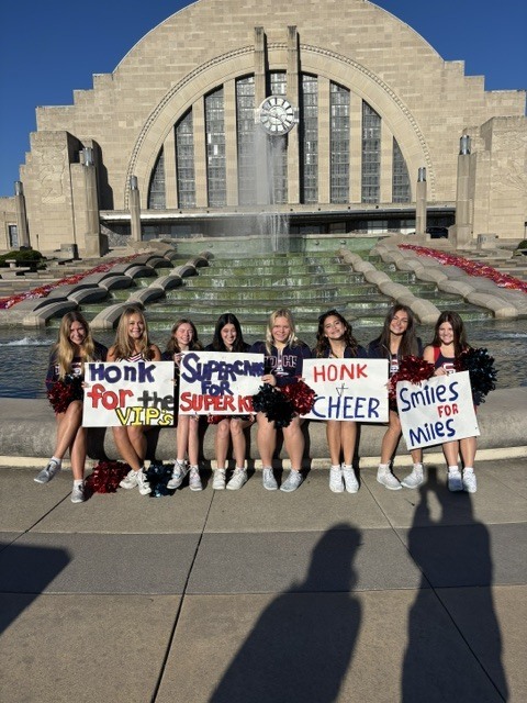 South Dearborn High School cheerleaders hold "Honk for the VIPs" and "Smiles for Miles" signs at Union Terminal in Cincinnati.