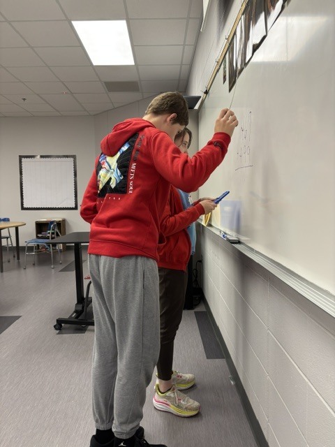 Two South Dearborn High School students work together on a math problem at the whiteboard during Applied Algebra practice.