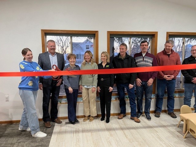 group of people cutting red ribbon in child care center
