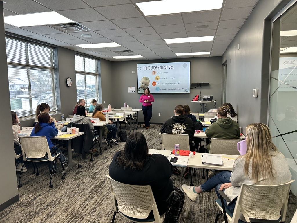 picture of people facing the front of a room with a presenter at the front