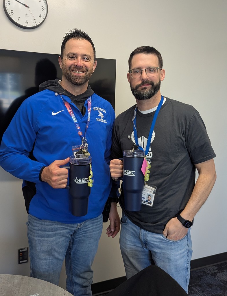 Kindred principals holding SEEC travel mugs smiling
