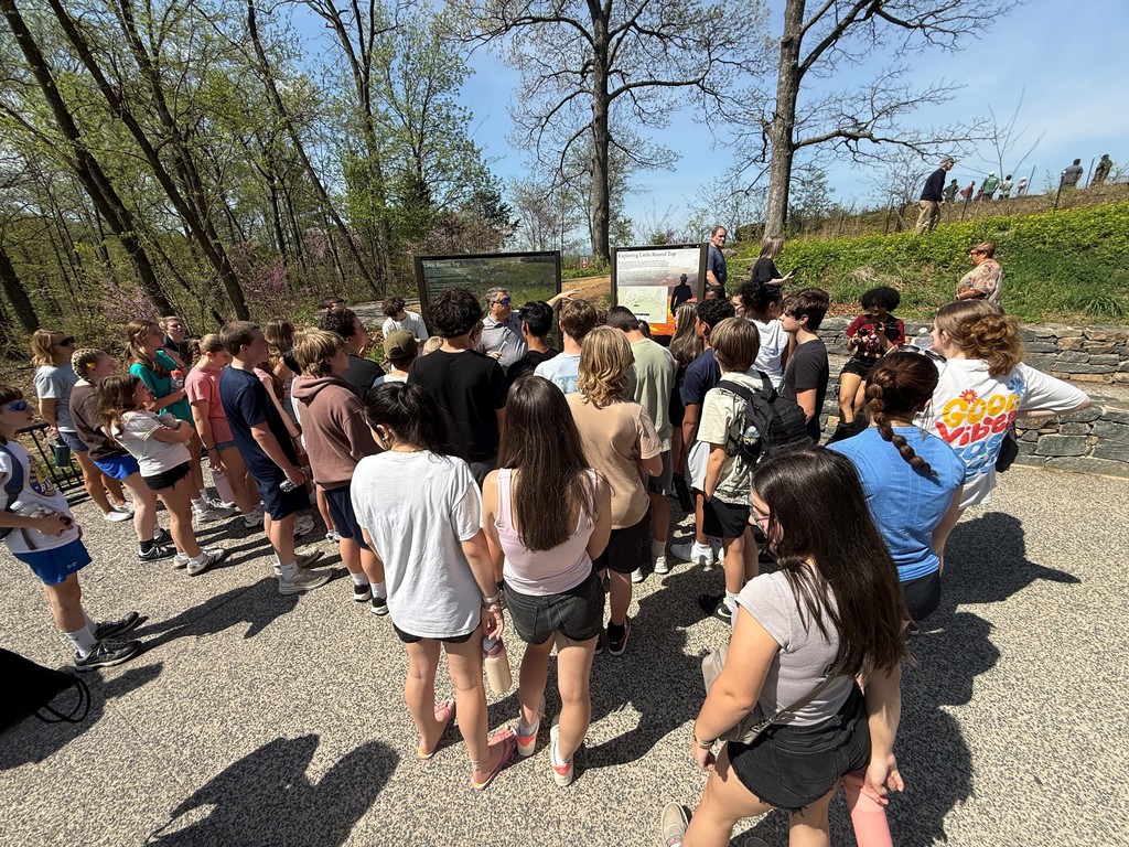 A group of students learning about Little Round Top from a Gettysburg tour guide.