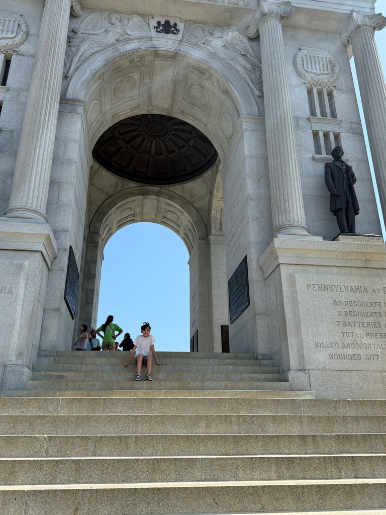 A student sitting on the stairs of a Gettysburg monument.