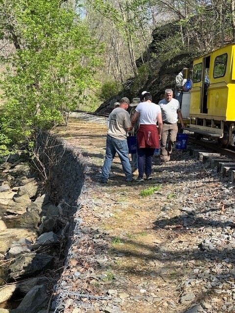 Students and adults getting buckets from a train to carry to the creek to stock trout.