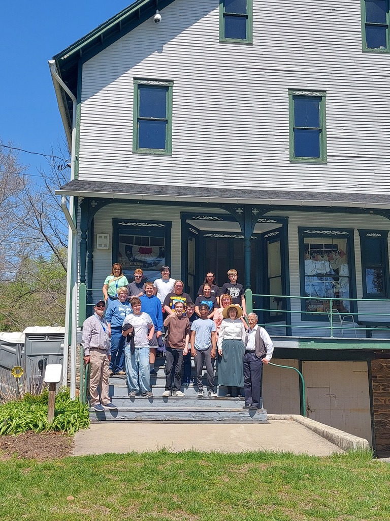 Students, staff and adults posing for a photo on the stairs of the Ma and Pa Railroad Heritage Village Museum.