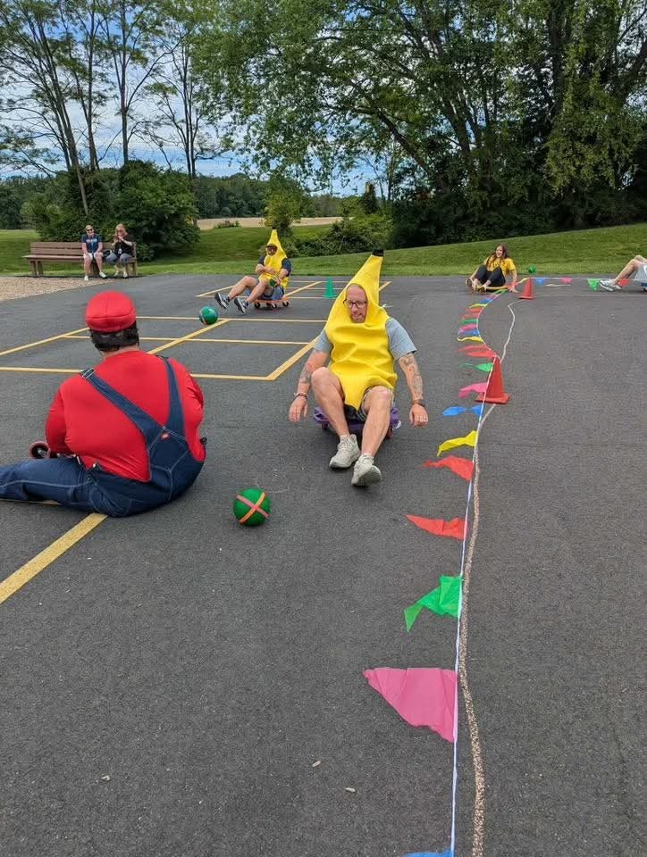Teachers dressed in Mario Brothers and banana costumes riding on scooters.
