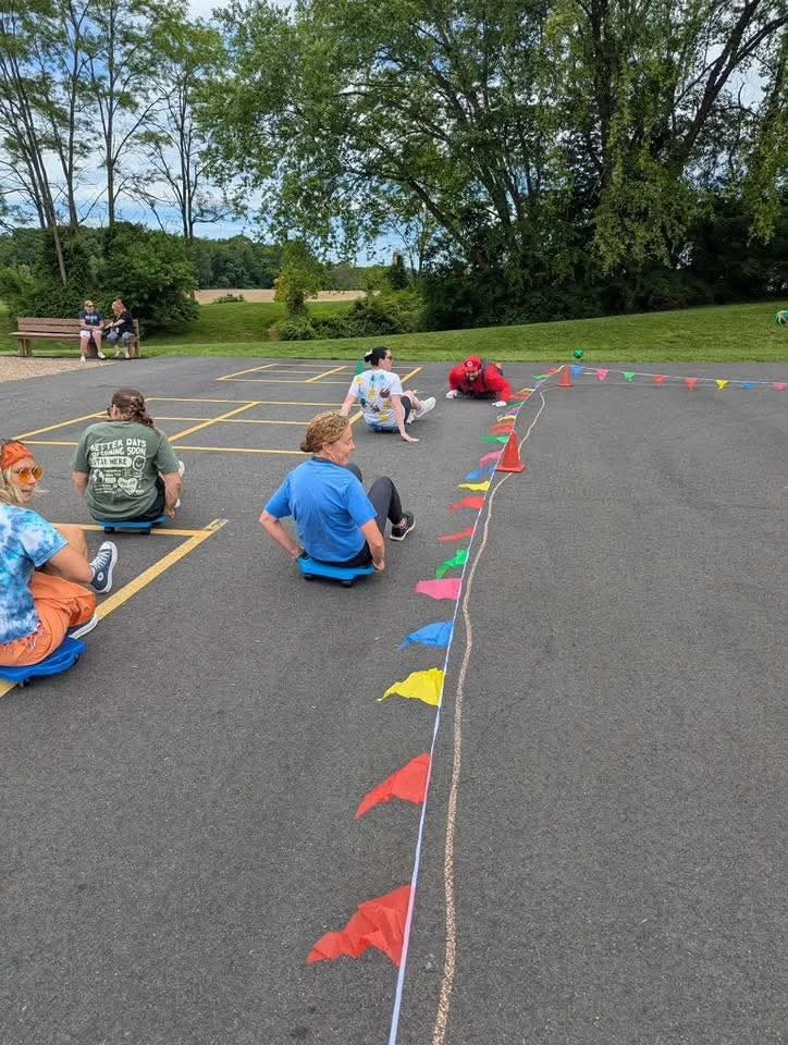 Teachers racing on scooters in a parking lot.