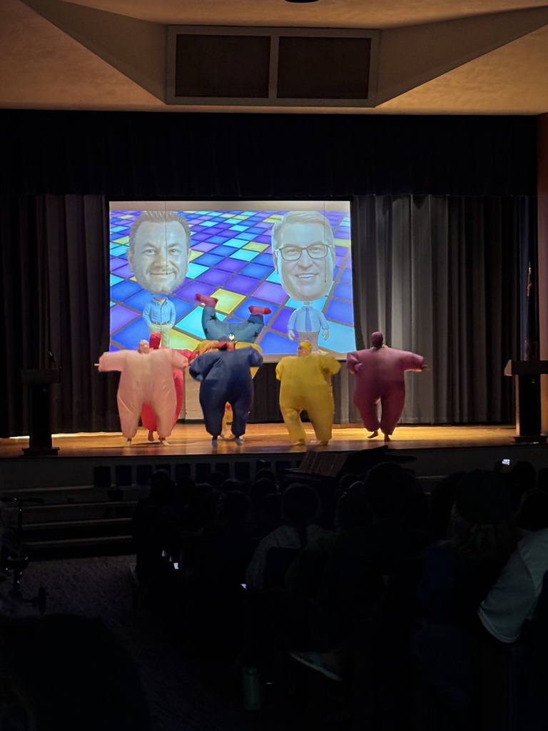 Four people on stage in blow up costumes doing a dance.