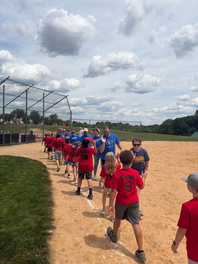 Students and staff in lines giving high fives and telling each other "good game" after the annual kickball game.
