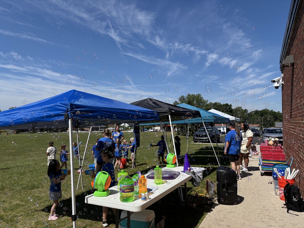 Groups of students blowing bubbles in the field near Stewartstown Elementary.