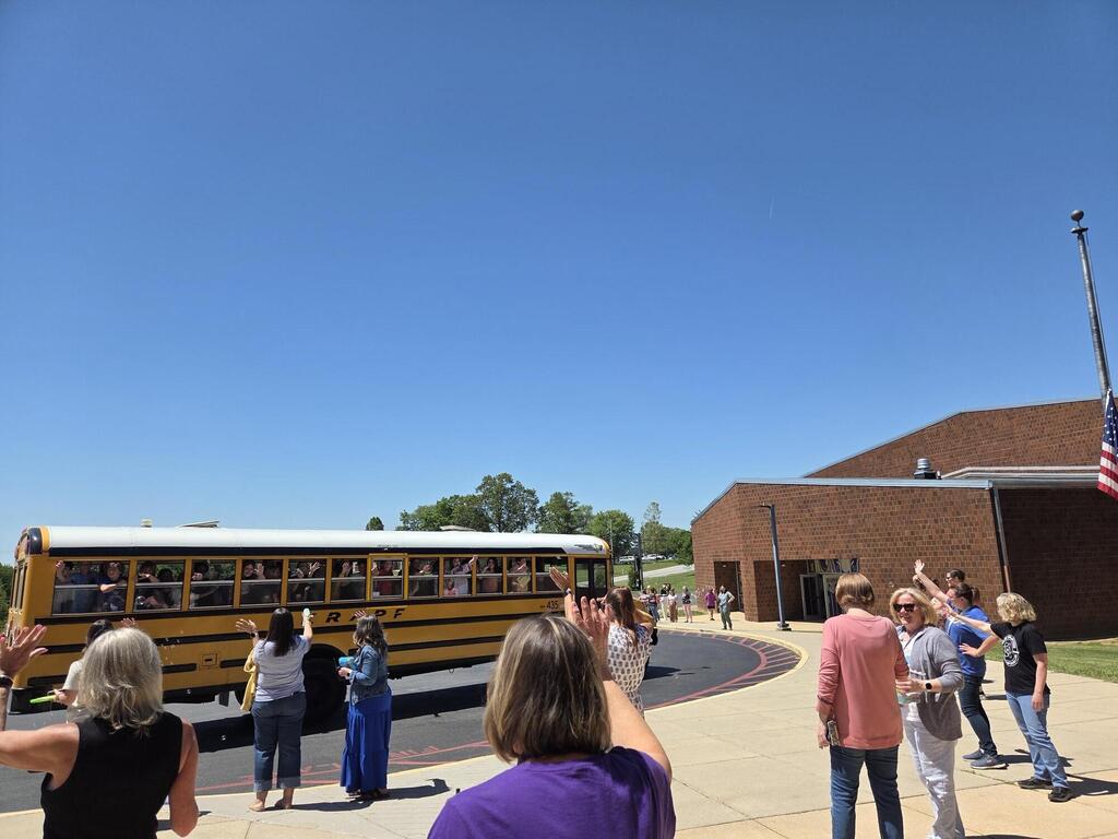 Staff at South Eastern Intermediate School waving goodbye to students on buses on the last day of school.