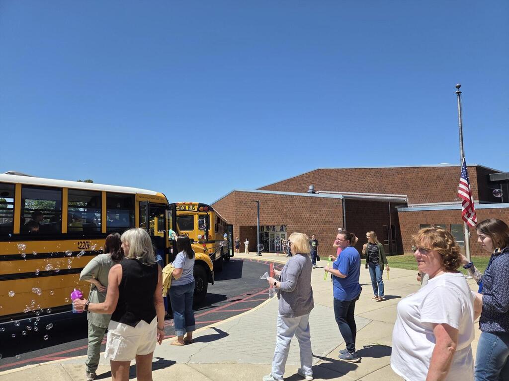 Staff saying goodbye to students at their buses on the last day of school.