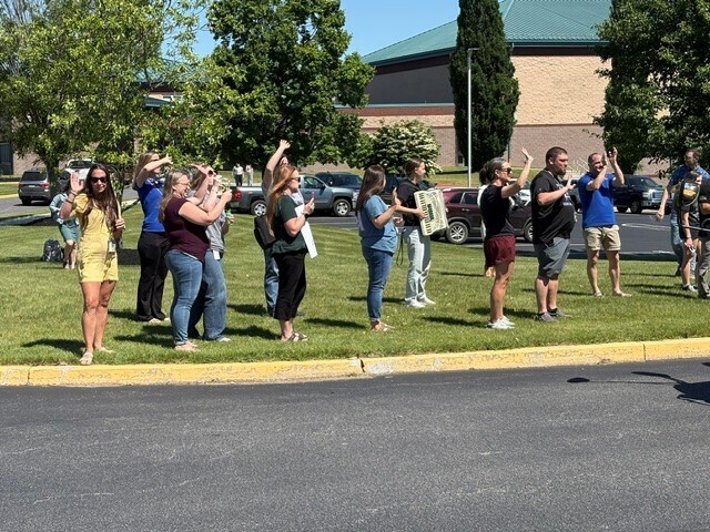 Teachers at KDHS holding signs and waving goodbye to students on the last day of school.