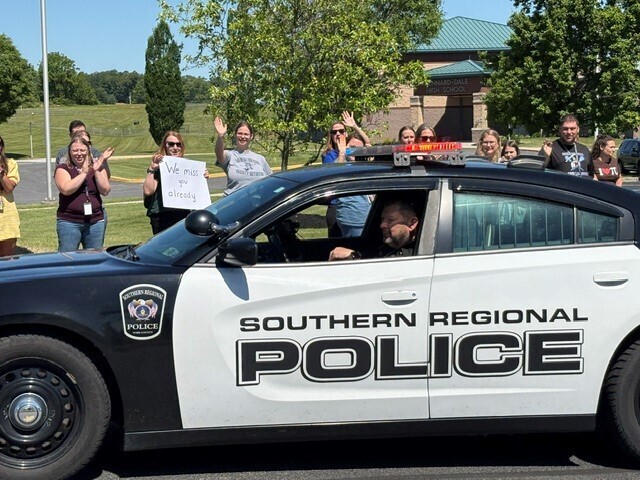 Resource officer, Detective Shaffer, getting  well wishes for his retirement as he leaves in his police vehicle  on the last day of school.