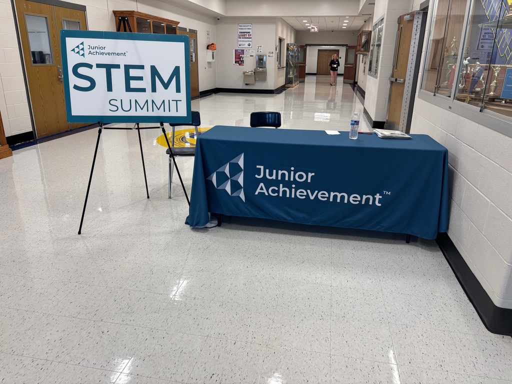Picture of the STEM Summit welcome table and placard in the hallway between the cafeteria and gymnasium at Kennard-Dale High School.