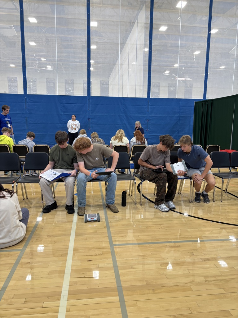 Students in a gymnasium working in pairs to complete an activity on robotics.