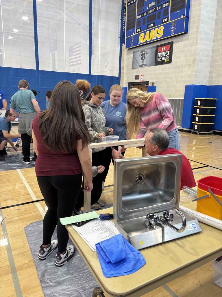 Group of students in a gymnasium participating in a hands on activity about plumbing.