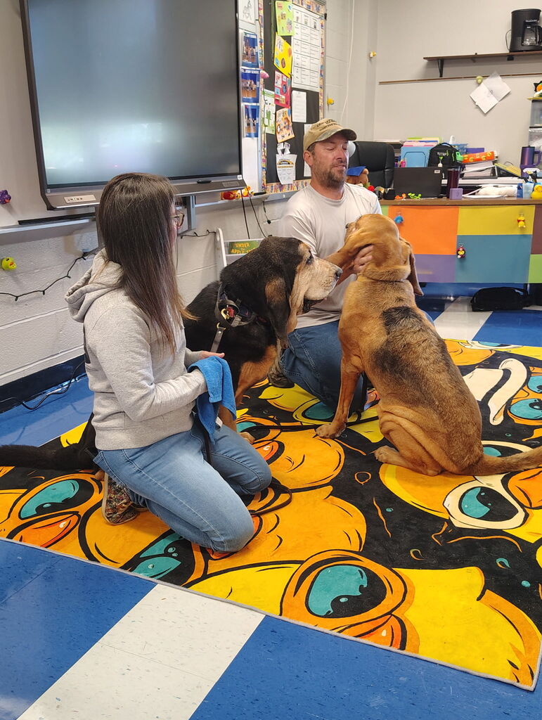 Two adults sitting with their two rescue dogs.