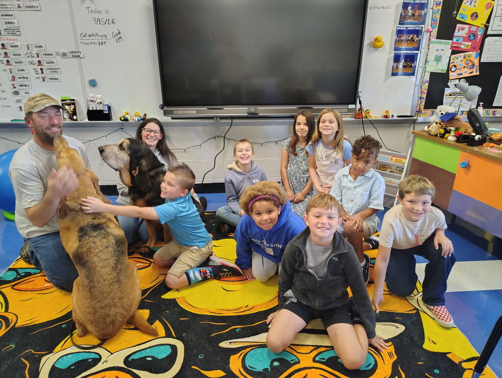 A group of students posing for a picture with two rescue dogs and their two handlers.