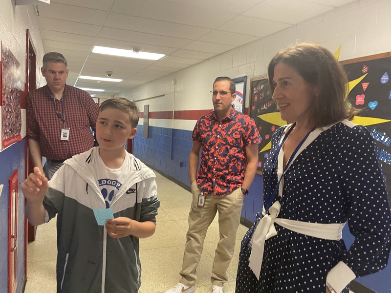 Three adults and a child stand in a hallway reviewing materials