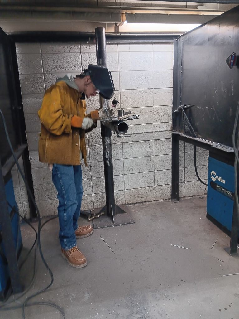 Maverick Barth (Gilman City) cleans his slag and spatter off of his finished SMAW project