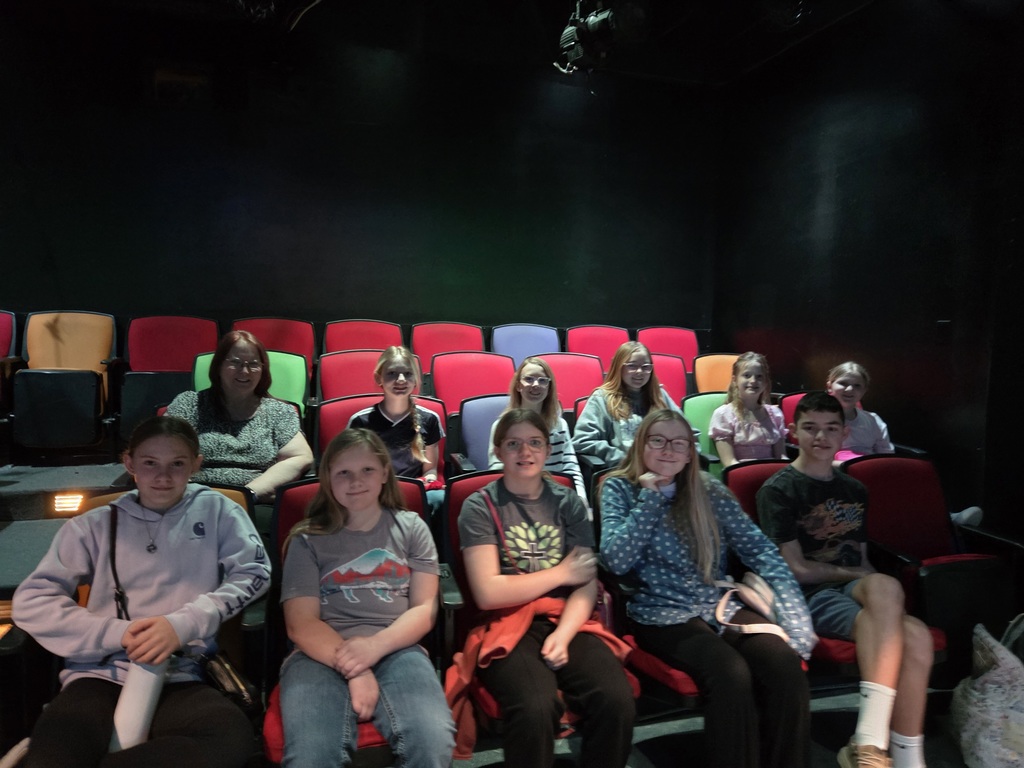 Students grades 4th thru 8th sitting in theater sitting chairs