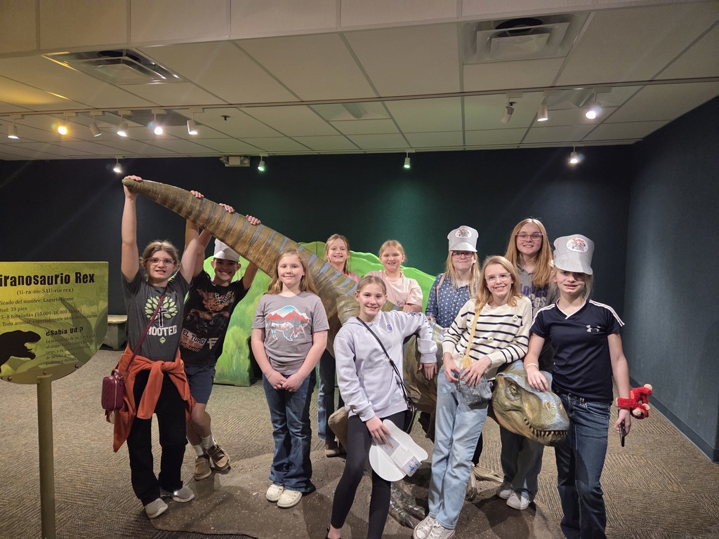 Students 4th thru 8th pose with a dinosaur replica