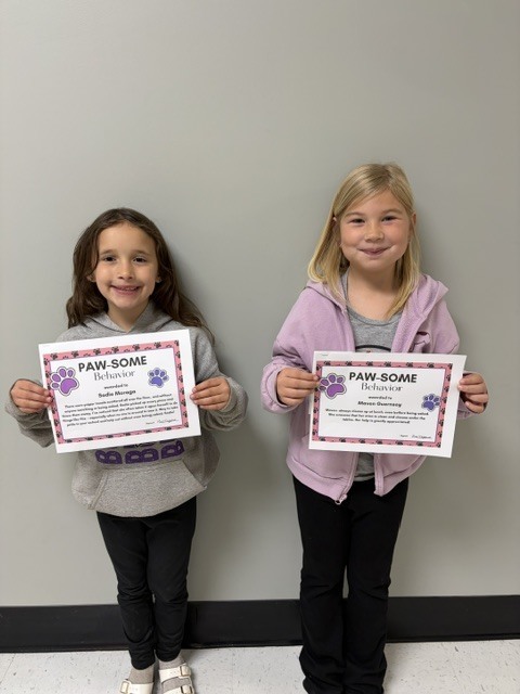 Photo of two students receiving PAWSitive Office Referrals. Sadie is pictured on the left and Maven on the right, recognized for their positive choices and great attitudes.