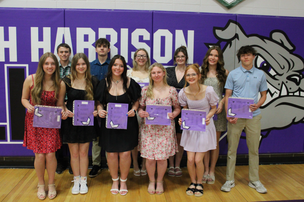 Junior students posing as a group, holding their academic certificates and chevrons in recognition of their achievements.