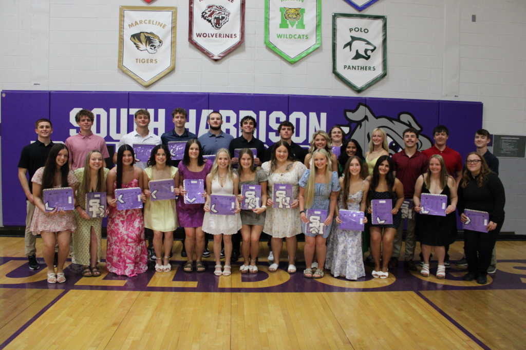 Senior students standing together, smiling and holding their academic certificates and chevrons during the Academic Banquet.
