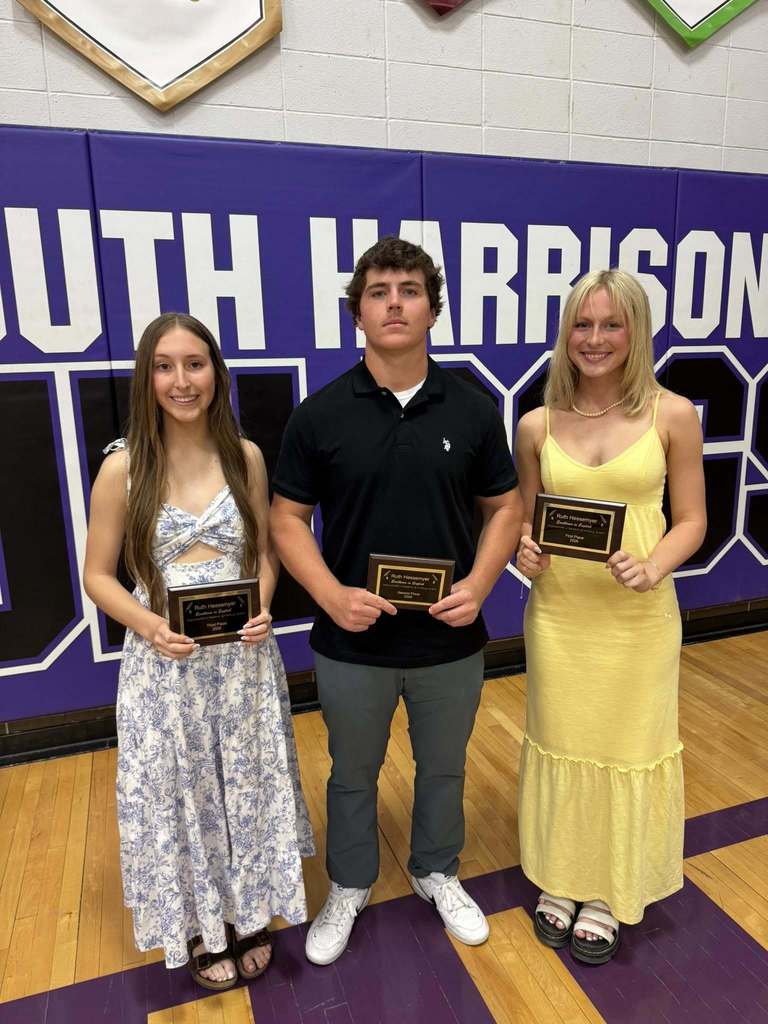 Three students stand side by side posing with their awards from the Ruth Hessemyer Argumentative Research and Writing Competition. From left to right: Abby Owens (third place), Joel McCall (second place), and Lexi Hunter (first place). All are smiling and dressed nicely, standing in front of a school backdrop