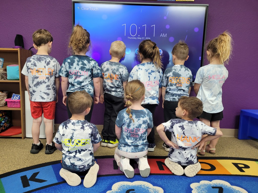 Preschool children from Miss Emily’s class proudly showing their field trip shirts while standing together, smiling and posing for a group photo during an end-of-year activity.