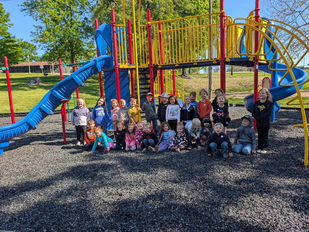4 year old preschoolers pose in front of the jungle gym at the park