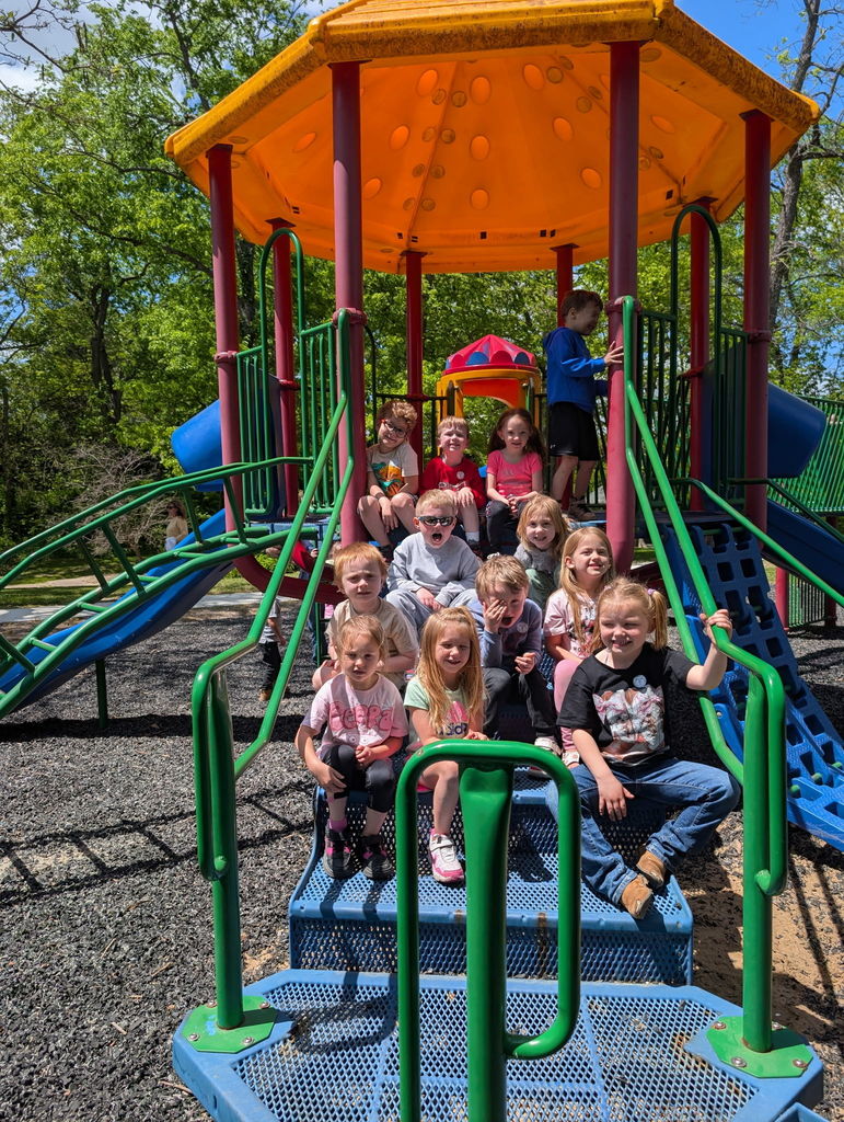 4 year old preschoolers pose of the steps of the jungle gym at the park