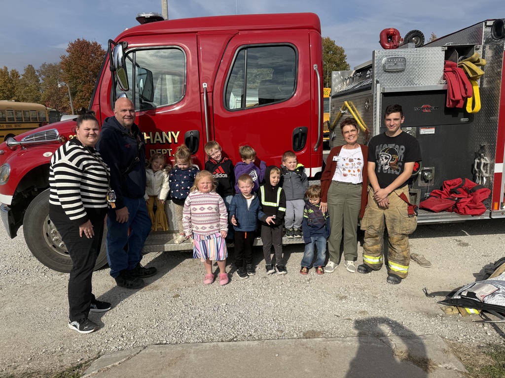 Preschool students learning about fire safety while exploring a fire truck, looking at firefighter equipment, and visiting with firefighters