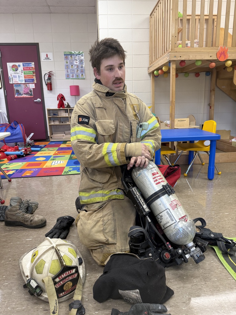 Preschool students learning about fire safety while exploring a fire truck, looking at firefighter equipment, and visiting with firefighters