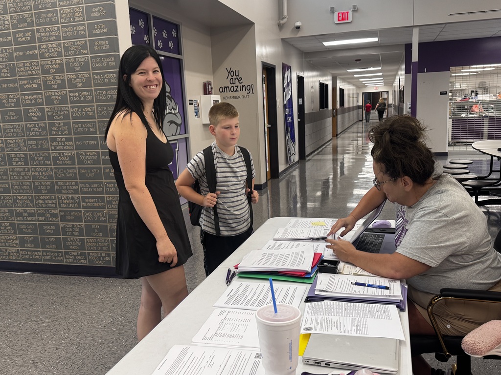 A mom and her incoming 5th grade son pick up his class schedule during middle school orientation.