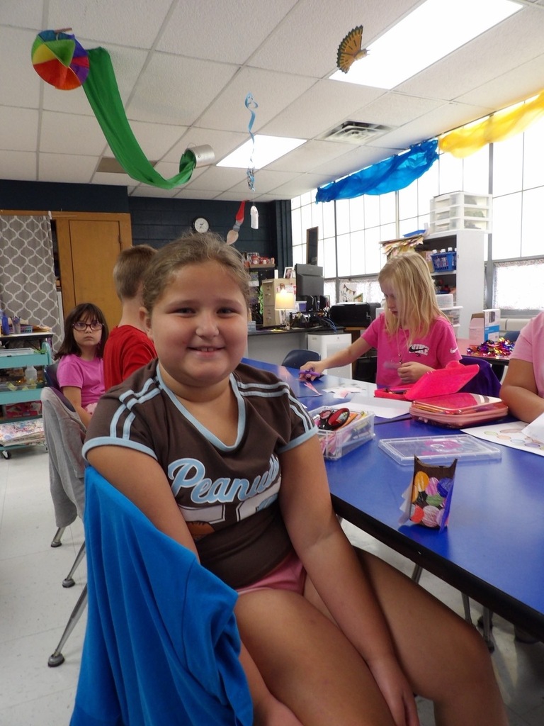 Photo of elementary student with owl project made in art class.