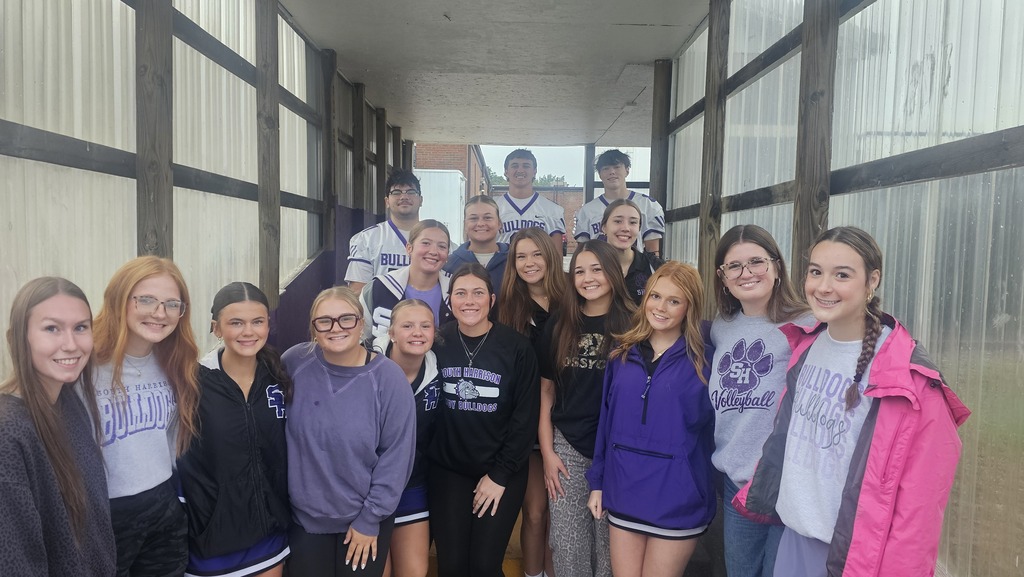 High school athletes pose for a picture in front of the Elementary school