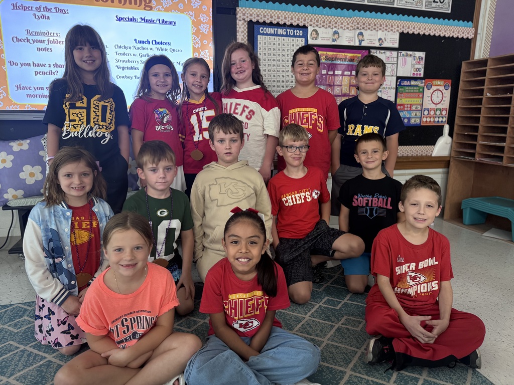 14 students posing for a picture of them in their souvenir shirts for homecoming dress up days