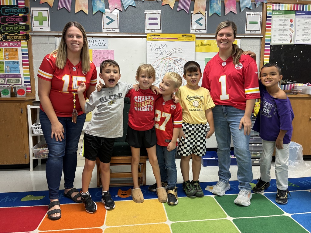 two teachers standing with 5 students wearing their souvenir shirts
