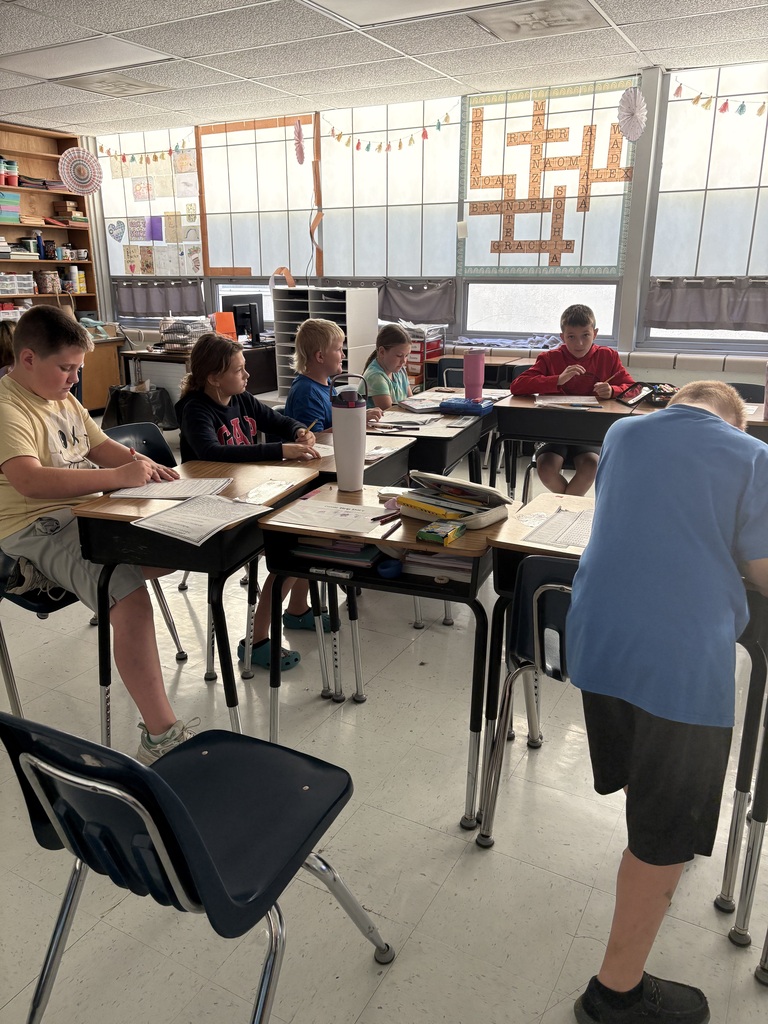 Students in class sitting at their desks, watching their teacher teach