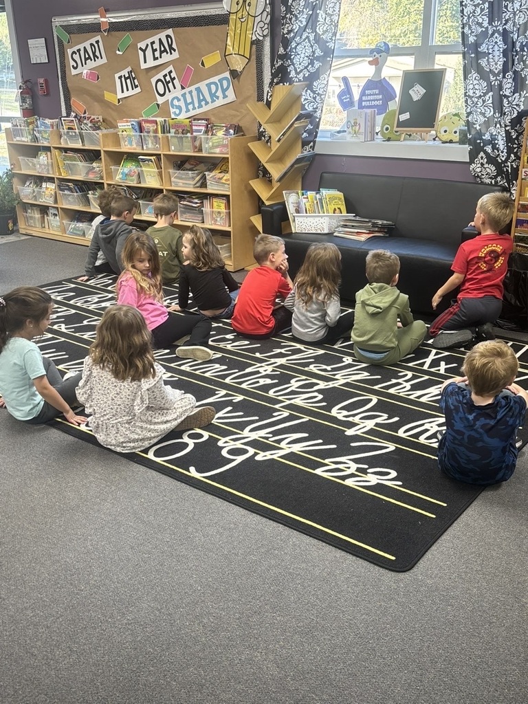 kindergarteners sitting on the floor in the library waiting for a book to be read to them
