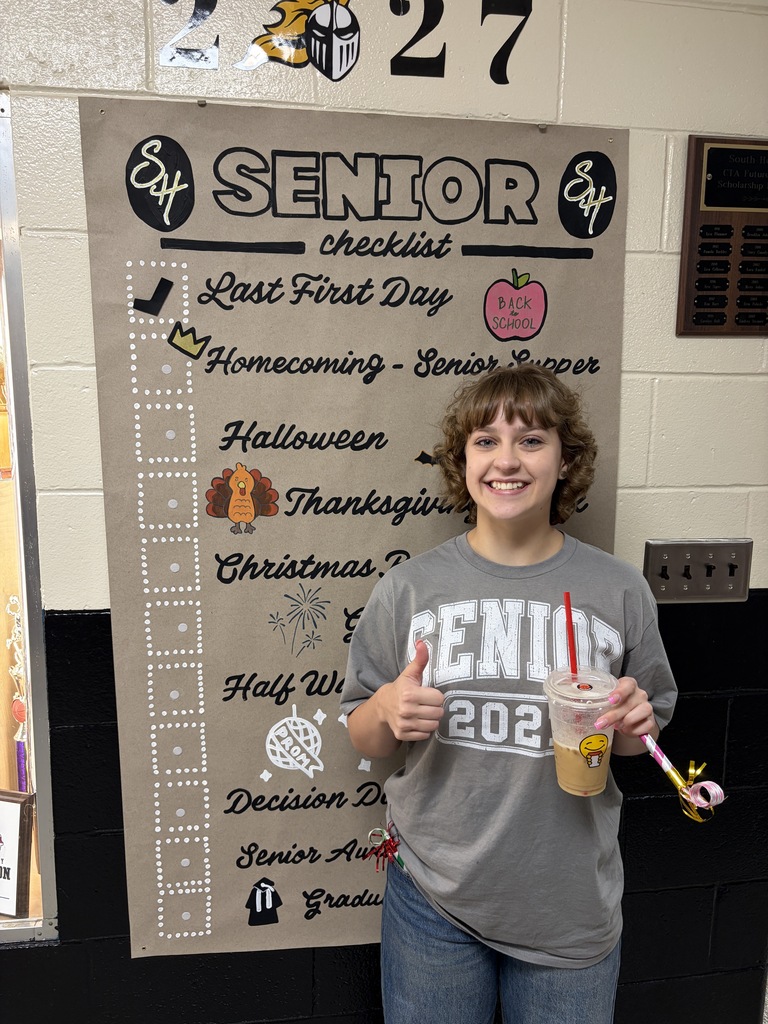student posing next to banner