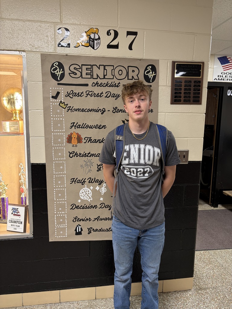 student posing next to banner